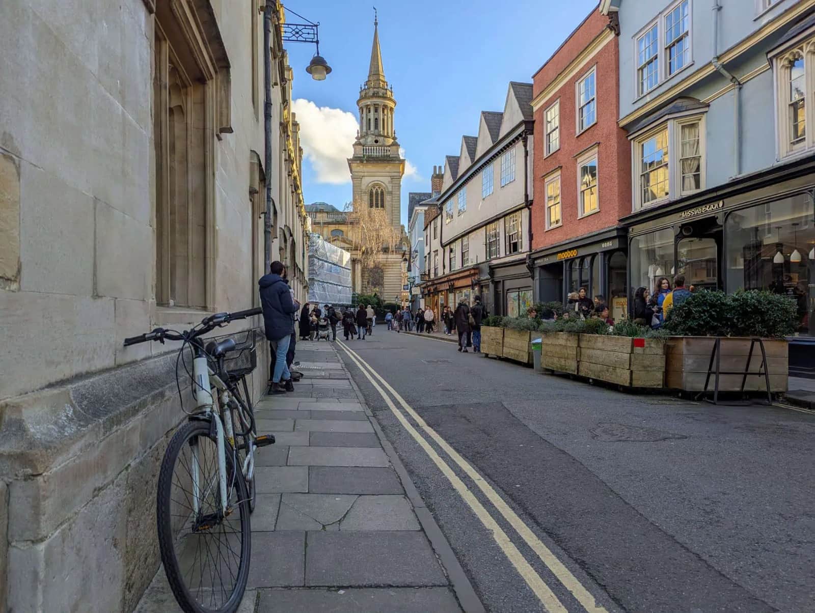 A cobbled street lined with shops and a spire in the distance